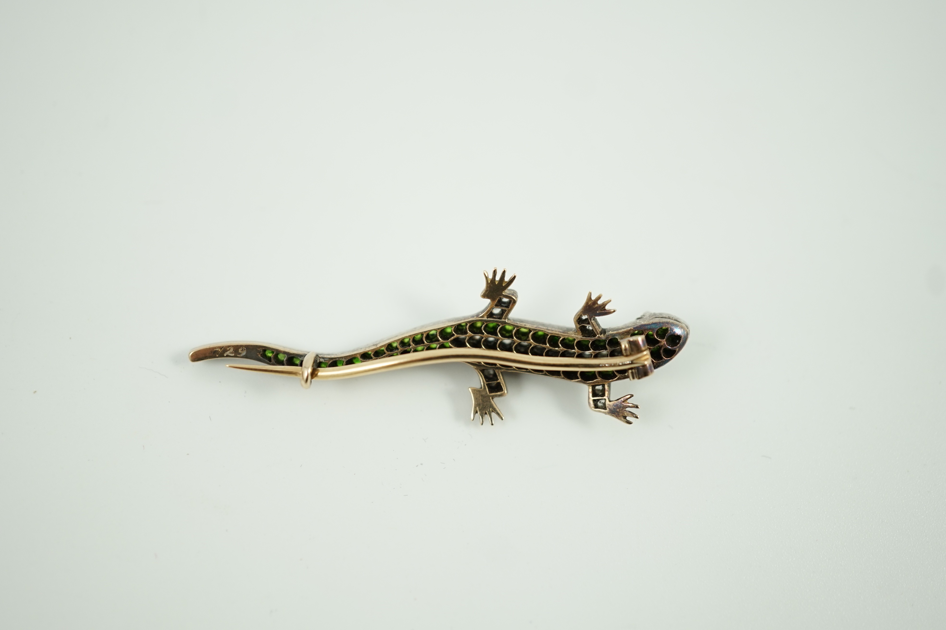 An Edwardian yellow metal, diamond and green garnet set lizard brooch, with red cabochon eyes, 50mm, gross weight 6.2 grams.